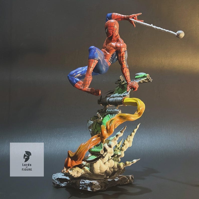Op de afbeelding: Een rood en blauw Spiderman-actiefiguur is in de lucht geposeerd en zwaait aan een web. De figuur zit op een groene en oranje basis met een rookwolk-effect. De basis is van plastic en heeft een rotsachtige textuur.