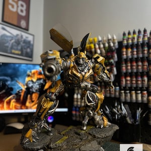 Könnte beinhalten: Detaillierte Bumblebee-Actionfigur in dynamischer Pose, überwiegend gelb und schwarz, mit metallischen Akzenten. Die Figur steht auf einer strukturierten Basis und zeigt komplizierte mechanische Details. Das Lord Figures-Logo ist sichtbar.