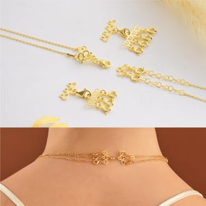May include: Gold necklace with a delicate chain and a decorative clasp. The clasp is made of multiple small circles and is designed to be worn as a layered necklace.