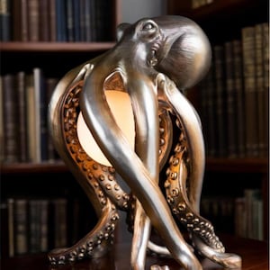 May include: A bronze-coloured octopus lamp with a round, glowing light source. The lamp features detailed tentacles and a textured surface, creating a unique decorative piece. The lamp is placed on a wooden surface, with a bookshelf in the background.