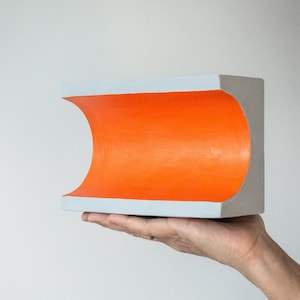Orange Groove – Escultura mural de cartón en gris hormigón y naranja
