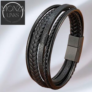 Puede incluir: Pulsera de cuero negro con m&uacute;ltiples hebras, incluyendo texturas trenzadas y lisas. La pulsera presenta un cierre magn&eacute;tico y el texto "MONZA LINKS MODERN JEWELLERY" en un logotipo circular.