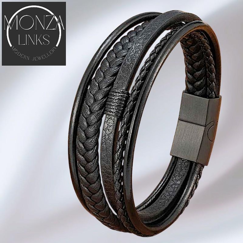 Puede incluir: Pulsera de cuero negro con m&uacute;ltiples hebras, incluyendo texturas trenzadas y lisas. La pulsera presenta un cierre magn&eacute;tico y el texto "MONZA LINKS MODERN JEWELLERY" en un logotipo circular.