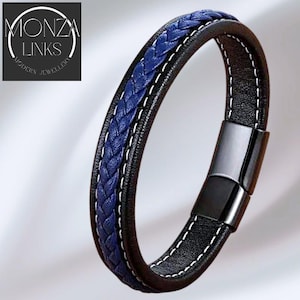 May include: Black and blue leather bracelet with a braided blue center and white stitching. The bracelet has a magnetic clasp and the text "MONZA LINKS MODERN JEWELLERY" in the upper left corner.