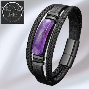 May include: Black leather bracelet with a braided design and a rectangular purple gemstone. The bracelet has a magnetic clasp and black metal accents. The text "MONZA LINKS MODERN JEWELLERY" is in the upper left corner.