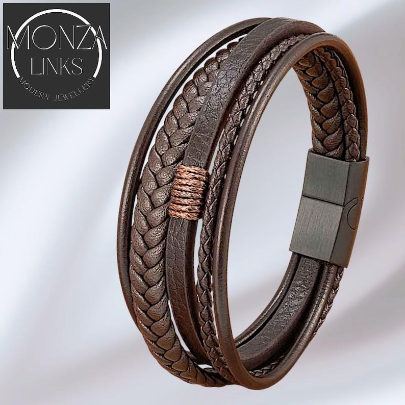 Puede incluir: Pulsera de cuero marr&oacute;n de m&uacute;ltiples hebras con cierre magn&eacute;tico. La pulsera presenta hebras de cuero trenzado y liso, con un acento de color cobre. La marca "MONZA LINKS MODERN JEWELLERY" est&aacute; en la esquina superior izquierda.