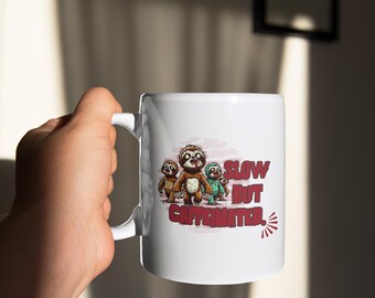 May include: White ceramic mug with a graphic of four sloths walking and the text "Slow but Caffeinated."