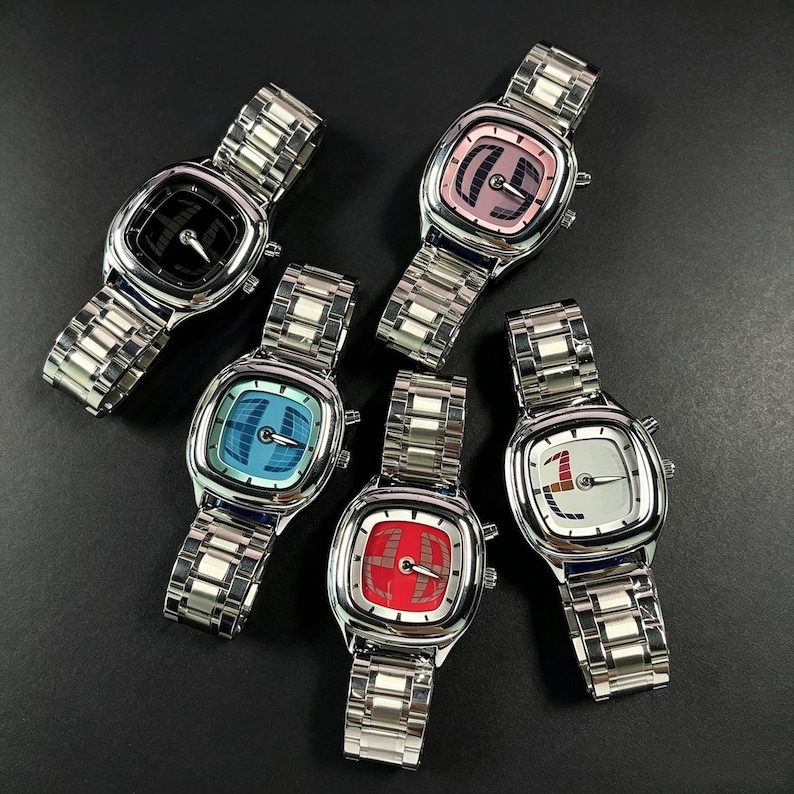 Puede incluir: Cinco relojes de pulsera de acero inoxidable con esferas cuadradas y correas de metal a juego. Cada reloj tiene una esfera de diferente color: negro, rosa, azul, rojo y blanco. Las esferas de los relojes tienen dise&ntilde;os gr&aacute;ficos &uacute;nicos.