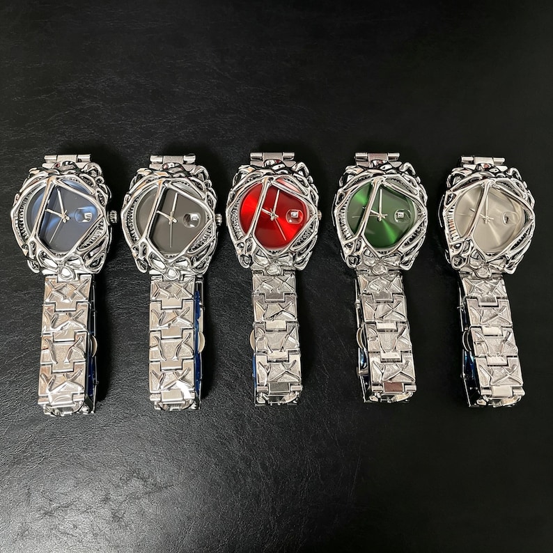 May include: Five unique wristwatches with silver-toned metal bands and intricate, cage-like bezels. Each watch features a different colored face: blue, gray, red, green, and silver. The watch faces have a geometric design.