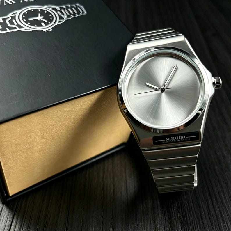 May include: A silver wristwatch with a brushed metal finish. The watch has a round face with silver hands and a matching silver band. The watch is next to a black box with the watch's image on the lid. The watch has the text "NIRUISI QUARTZ WATCH".