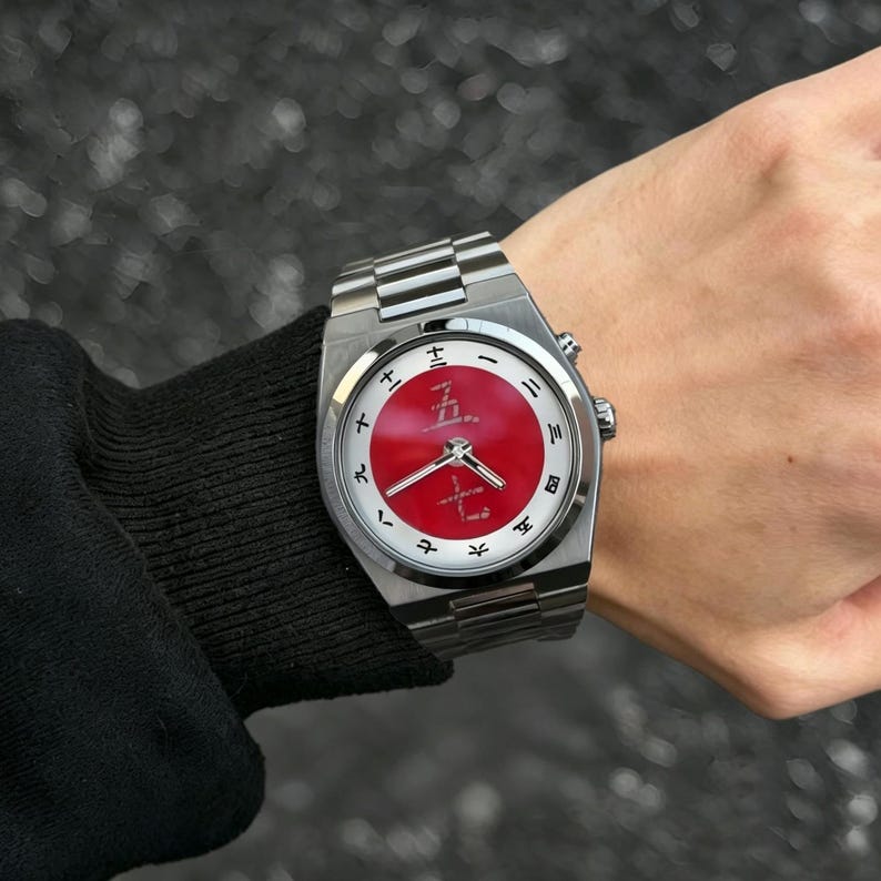 May include: A stainless steel wristwatch with a metallic link band, featuring a circular white dial with a vibrant red center. The dial displays black Japanese kanji numerals for the hours and includes silver-toned hour, minute, and second hands.