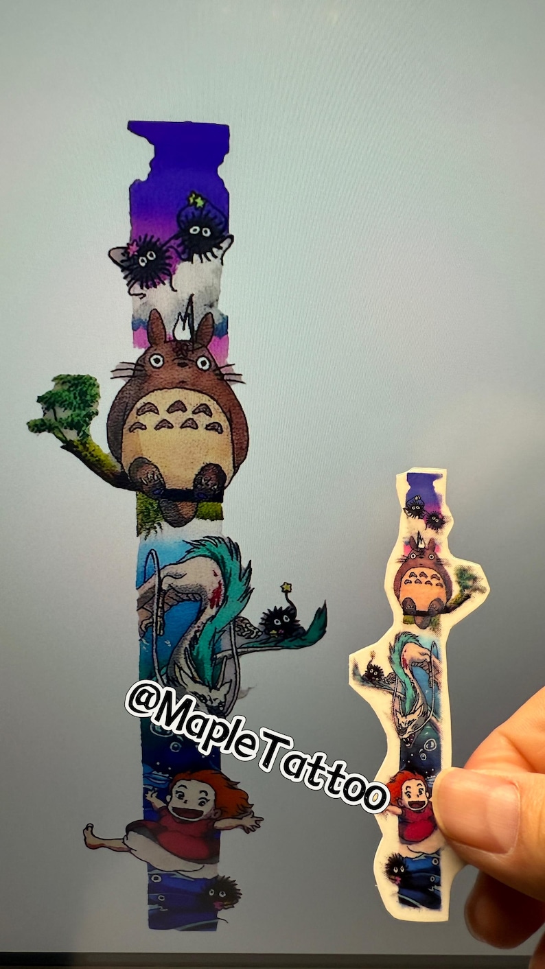 K&ouml;nnte beinhalten: Ein vertikales Tattoo-Design mit Figuren aus dem Animationsfilm Mein Nachbar Totoro. Das Design beinhaltet Totoro, die Ru&szlig;geister und ein junges M&auml;dchen. Das Design ist farbig und hat einen verspielten Stil. Der Text "@MapleTattoo" ist am unteren Rand des Designs sichtbar.