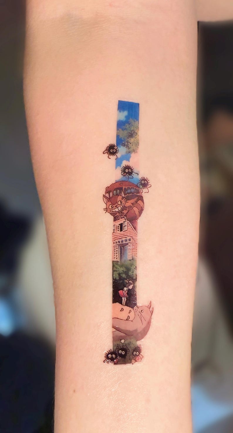 K&ouml;nnte beinhalten: Ein Tattoo, das eine Szene aus dem Animationsfilm 'Mein Nachbar Totoro' zeigt. Das Tattoo zeigt einen fliegenden Katzenbus, ein junges M&auml;dchen und mehrere Ru&szlig;geister.