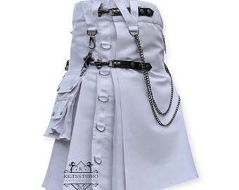 Könnte beinhalten: Ein weißer Kilt mit mehreren Taschen, Riemen und Metallbeschlägen. Der Kilt hat einen schwarzen Ledergürtel, eine dekorative Kette und ein Logo am unteren Rand. Der Kilt besteht aus einem robusten Material und hat ein plissiertes Design.