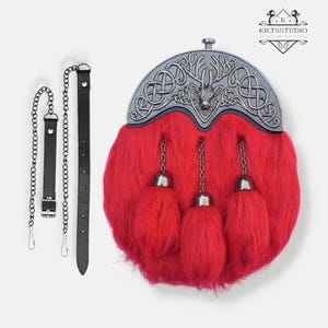 Puede incluir: Un sporran de kilt escocés rojo con una parte superior de metal plateado con un diseño de ciervo y nudos celtas. El sporran tiene tres borlas decorativas y viene con una correa y cadena de cuero negro.