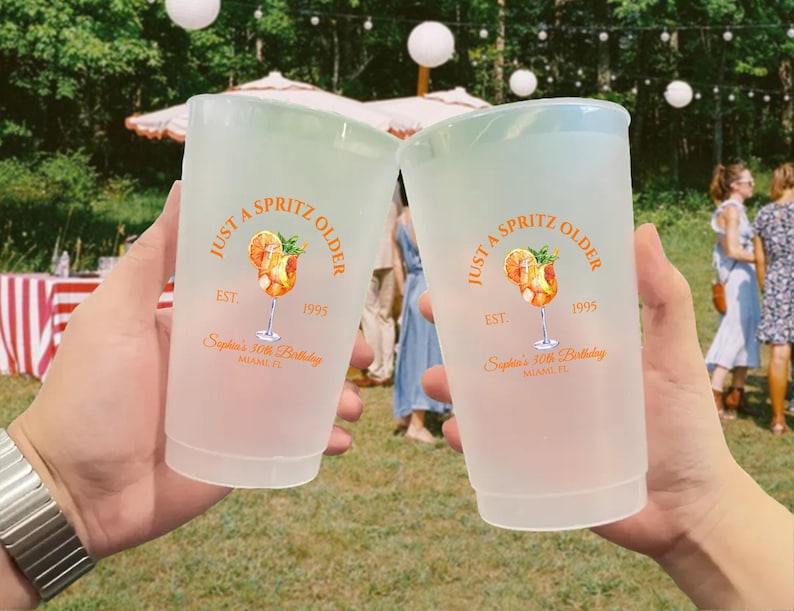 May include: Two frosted plastic cups with a light green rim, each bearing the text "Just a Spritz Older" and a cocktail illustration. The cups are personalized for "Sophia's 30th Birthday" in Miami, FL, with the year 1995.