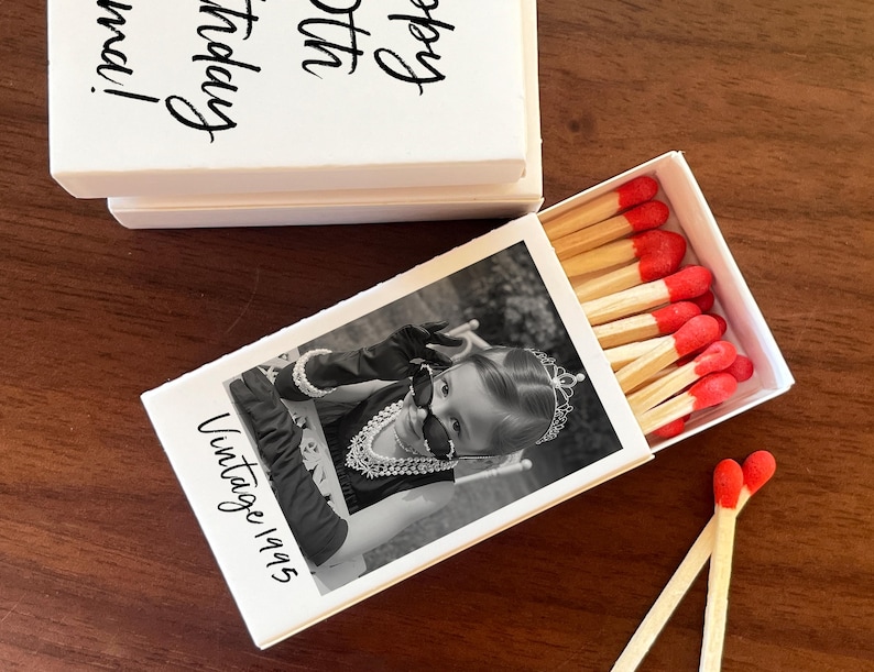 Op de afbeelding: Witte luciferdoos met een zwart-wit foto van een kind met een zonnebril en de tekst "Vintage 1995". De luciferkoppen zijn rood. De bovenkant van de doos heeft de tekst "Happy 30th Birthday, Anna!"