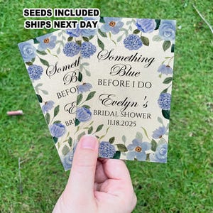 May include: A light blue and white floral design with the text "Something Blue Before I Do Evelyn's Bridal Shower 11.18.2025".