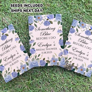 May include: Three blue and white floral patterned cards with the text "Something Blue Before I Do Evelyn's Bridal Shower 11.18.2025" printed on each card.