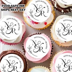 May include: An overhead shot of several cupcakes with white frosting and decorative toppers. The toppers feature the names "Nova & Ryan" and the date "08.15.2026" in black script. The text "FOOD-SAFE INK SHIPS NEXT DAY" is also visible.