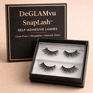 May include: A black box with gold trim displays the text "DeGLAMvu SnapLash" and "SELF-ADHESIVE LASHES". Inside, two pairs of black, natural-looking false eyelashes are visible. The box is open, revealing the product.
