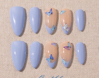 May include: A set of light blue and butterfly-decorated false nails. Some nails are solid light blue, while others feature a nude base with a light blue tip and butterfly accents. The word "Beautiful" is written on the bottom.