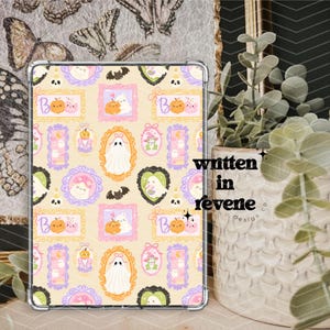 May include: A clear tablet case featuring a repeating pattern of Halloween-themed illustrations. The design includes ghosts, pumpkins, bats, and framed images in pastel colors. The text "written in revene design co." is visible.