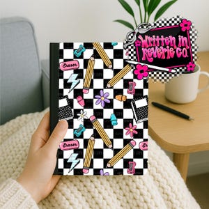 Könnte beinhalten: Ein rechteckiges Notizbuch mit schwarz-weißem Schachbrettmuster, verziert mit Illustrationen von gelben Bleistiften, rosa Radiergummis, blauen Blitzen und violetten Blumen. Ein Logo in der Ecke trägt die Aufschrift Written in Reverie Co.