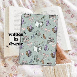 Könnte beinhalten: Ein hellblauer Hintergrund mit einem sich wiederholenden Muster aus Büchern, Kristallen, Schleifen und Blumen. Der Text "written in revenge" ist unten links sichtbar.