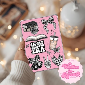 Op de afbeelding: Roze tablet hoesje met stickers van boeken, een strik, een koffie en een vlinder. De tekst "IN MY BOOKISH ERA" is zichtbaar. De hoes heeft ook een logo met de tekst "Written in Reverie Design Co."