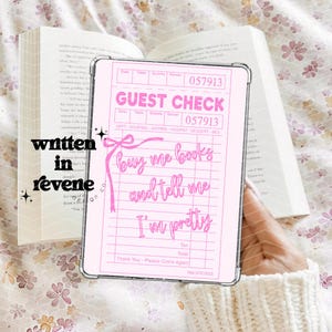 May include: A pink guest check with the words "GUEST CHECK" and "buy me books and tell me I'm pretty" in cursive. The check is held over an open book with the words "written in revene" on the side.