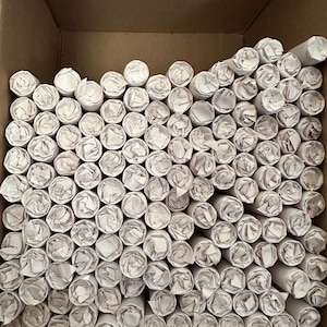 May include: A cardboard box filled with tightly rolled white paper tubes.