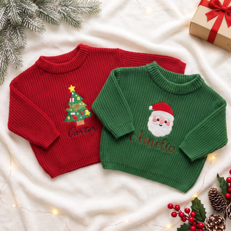 May include: A red knit sweater featuring an embroidered Christmas tree and the name Carter, and a green knit sweater featuring an embroidered Santa Claus face and the name Amelia, both with long sleeves and ribbed crew necklines.