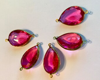 Puede incluir: Cinco cuentas de cristal rosa en forma de lágrima con detalles en metal dorado. Las cuentas tienen un diseño facetado y están enhebradas en un alambre de metal dorado.
