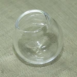 May include: A clear glass bowl with a rounded shape. The bowl is empty and has a smooth, shiny surface.