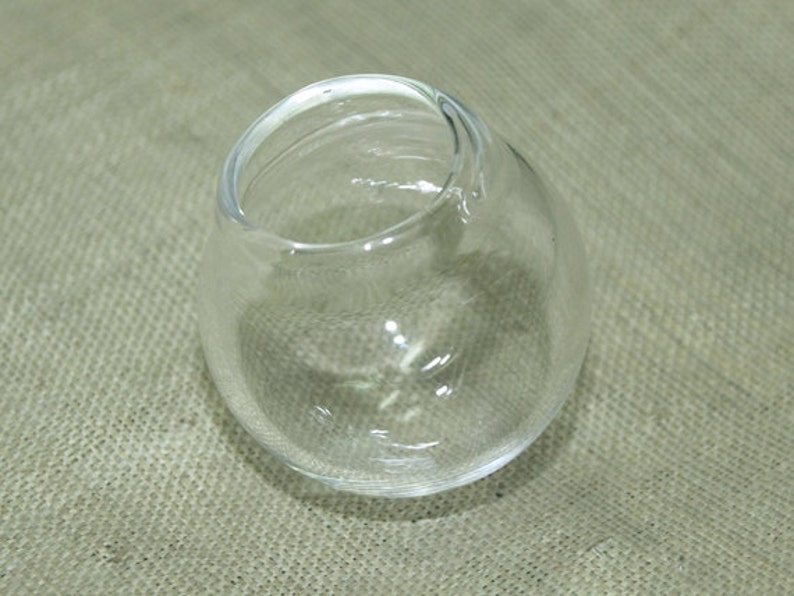 May include: A clear glass bowl with a rounded shape. The bowl is empty and has a smooth, shiny surface.