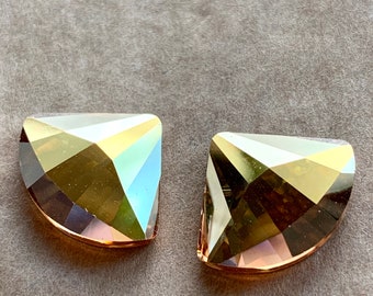 May include: Two gold-toned crystal rhinestones in a half-moon shape. The rhinestones have a faceted design and a clear, iridescent finish.