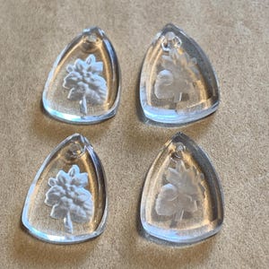 May include: Four clear glass triangle-shaped pendants with a white floral design etched into the glass.