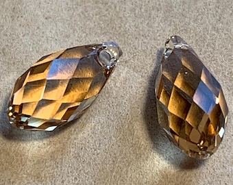May include: Two teardrop-shaped crystal pendants with a faceted design. The pendants are a light brown colour with a gold sheen.