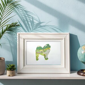 May include: A white framed print with a green and yellow illustration of a dog with a forest scene inside its silhouette. The print is on a white shelf with a potted plant and a globe on either side.
