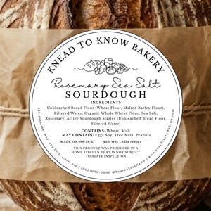 May include: A loaf of sourdough bread with a brown crust, wrapped in brown paper and twine. A circular label reads "Knead to Know Bakery" and lists ingredients, including rosemary and sea salt. Net weight is 1.5 lbs (680g).