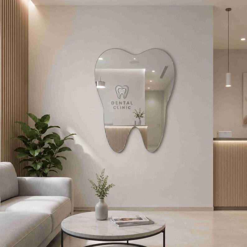 May include: A wall-mounted mirror shaped like a human tooth with a smooth, reflective surface. The mirror reflects a room interior featuring a sign that reads DENTAL CLINIC with a tooth icon above the text, positioned on a light-colored wall.