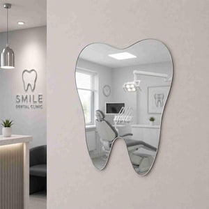 May include: A wall-mounted mirror shaped like a human tooth with a thin silver frame. The reflective surface shows a dental office interior, including a patient chair, medical lighting, and a window with blinds, creating a clear, bright reflection.