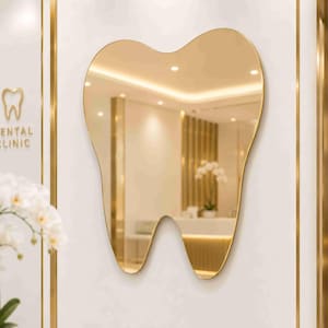 May include: A wall-mounted mirror shaped like a human tooth with a thin gold-toned frame. The reflective surface shows a blurred interior space with warm lighting and a white orchid. The wall features a gold tooth icon and the text DENTAL CLINIC.