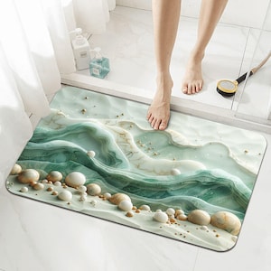 May include: A rectangular bath mat with a 3D wave design in shades of green, white, and beige. The mat features a textured surface with rounded stone-like accents. A person's feet are visible on the mat.