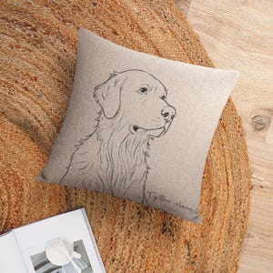 May include: A square beige throw pillow featuring a detailed line drawing of a Golden Retriever's head in profile. The pillow has the text "Together, always" in a handwritten font. The pillow is on a round, woven jute rug.