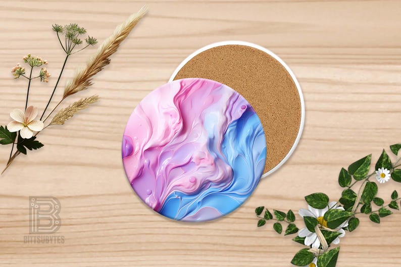 Puede incluir: Un posavasos redondo con borde blanco, con un dise&ntilde;o abstracto en espiral en tonos rosa, morado y azul. El posavasos se combina con un posavasos con respaldo de corcho. Elementos florales decorativos est&aacute;n dispuestos alrededor.