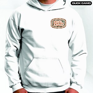 May include: White hooded sweatshirt with a camouflage patch that says "Girl Dad" in orange letters.