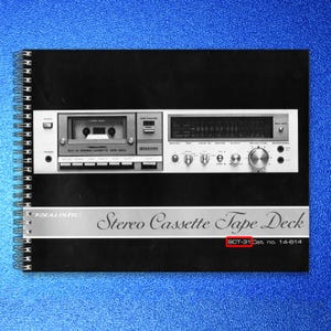 May include: A Realistic SCT-31 Stereo Cassette Tape Deck, shown on a black spiral-bound notebook. The deck has a silver face with various buttons, dials, and a tape counter. The text "Stereo Cassette Tape Deck" is displayed.