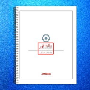 May include: A white spiral-bound user guide with the text "Artistic Digitizer User Guide" in a red box, and the brand name "JANOME" at the bottom. The background is a textured blue.